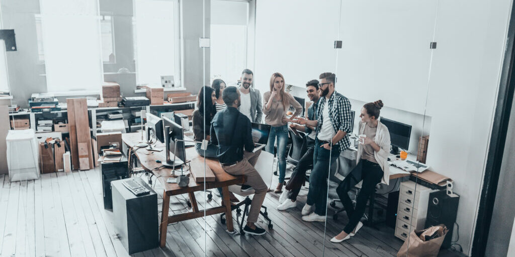 cooperation in action. full length top view of young business people in smart casual wear talking and smiling while having a brainstorm meeting in office